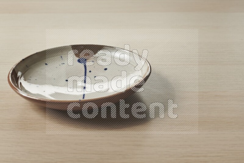 A multicolored pottery plate on light wooden background