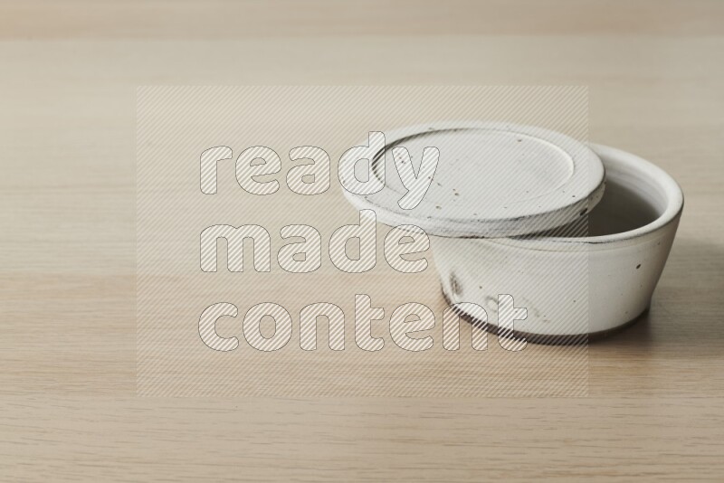 A white pottery bowl on light wooden background