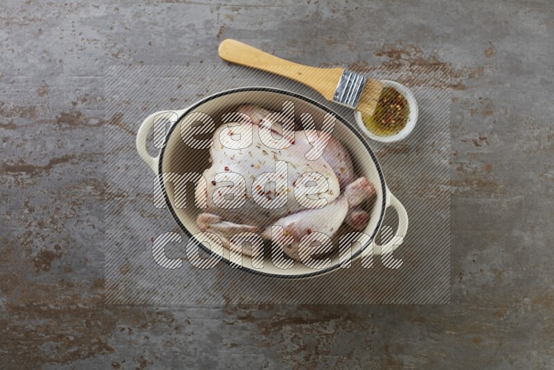 whole raw chicken on in a white ceramic pot direct on a rustic grey background