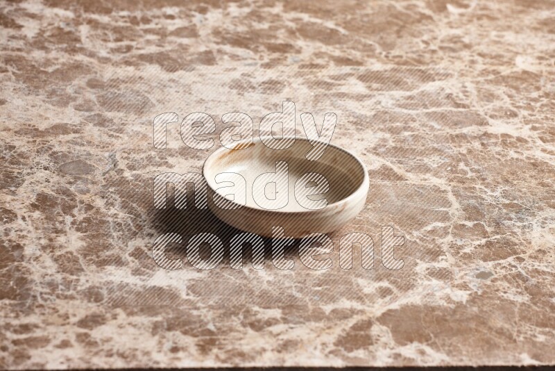 A beige pottery bowl on beige marble background