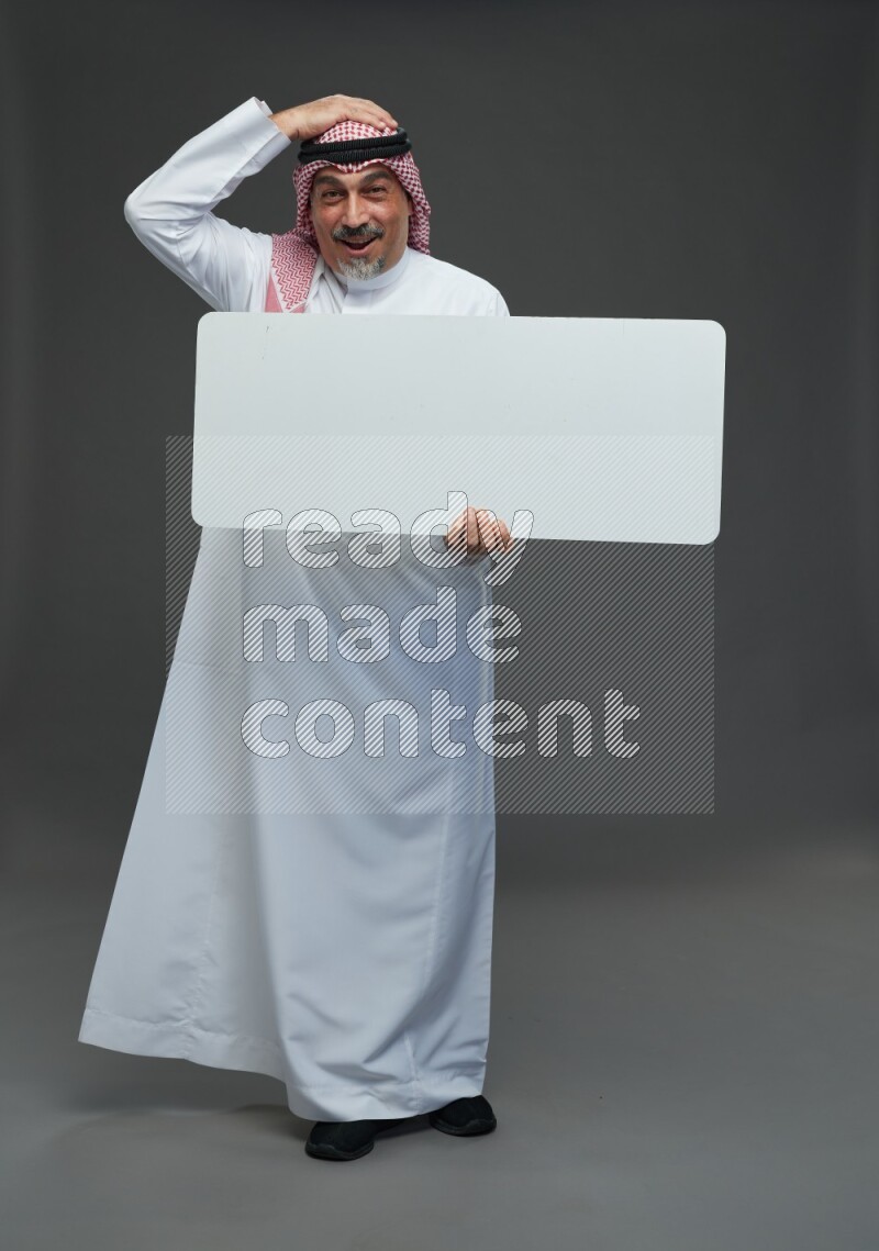 Saudi man with shomag Standing holding social media sing on gray background
