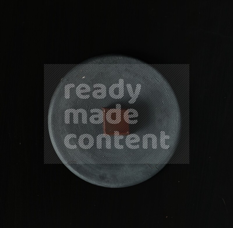 Assorted desserts in a black pottery plate on black background