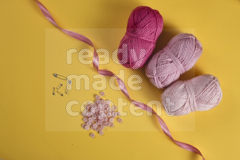 مجموعة من أدوات الخياطة والتفصيل زهرية اللون على خلفية صفراء