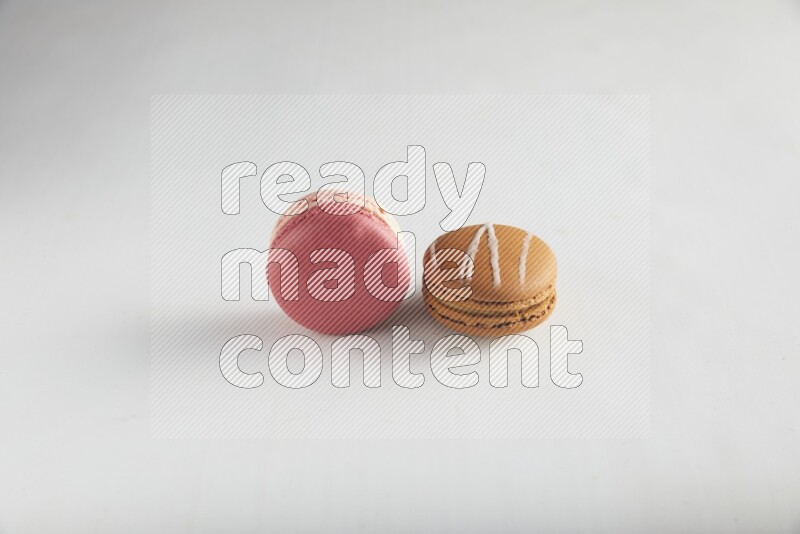 45º Shot of of two assorted Brown Irish Cream, and Pink Litchi Raspberry macarons on white background