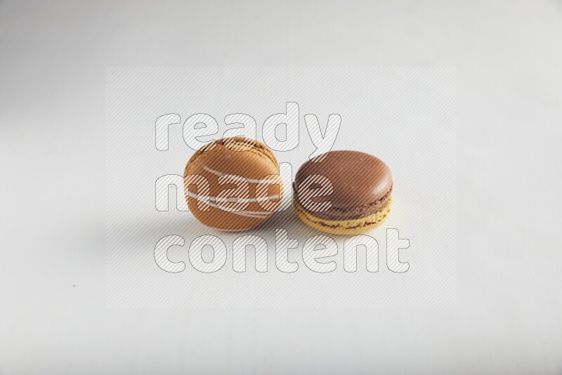 45º Shot of of two assorted Brown Irish Cream, and Yellow, and Brown Chai Latte macarons on white background