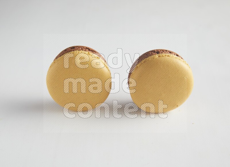 45º Shot of two Yellow and Brown Chai Latte macarons on white background