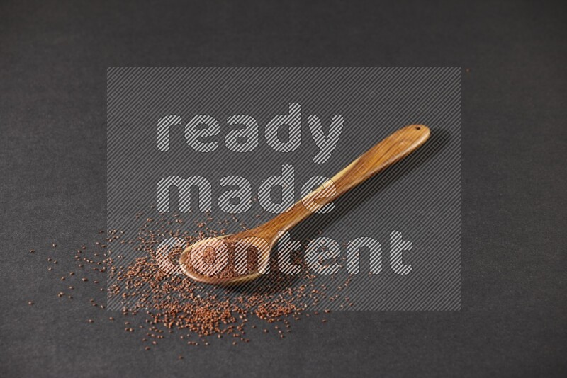 ملعقة خشبية كبيرة ممتلئة ببذور حب الرشاد وبعض البذور متناثرة علي خلفية سوداء