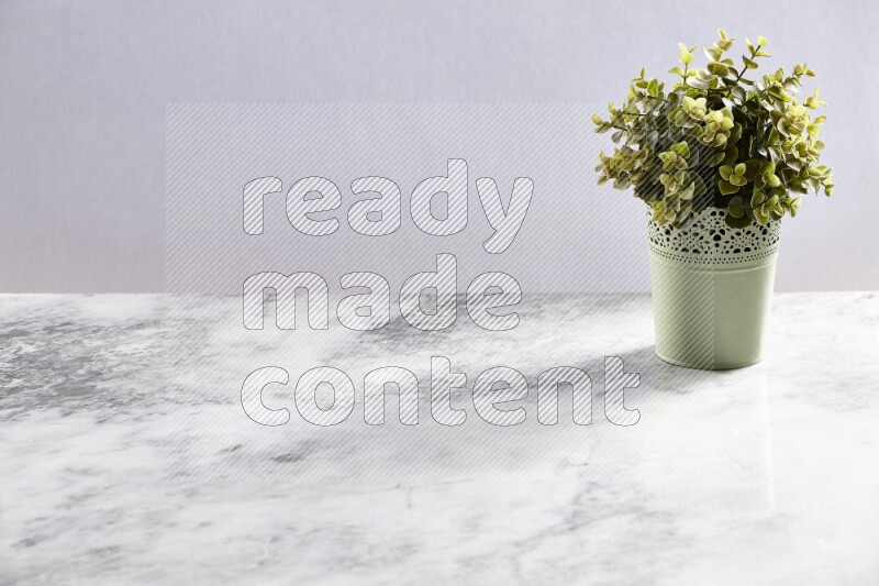 Artificial plant in green decorative pot on grey marble background