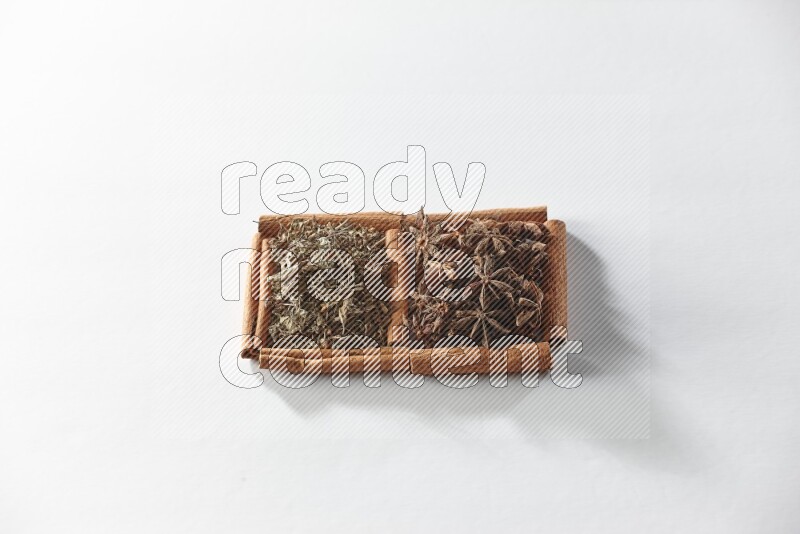 2 squares of cinnamon sticks full of star anise and dried basil on white flooring