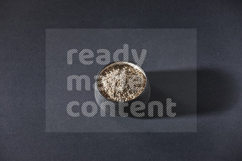 وعاء فخار أسود مملوء بالفلفل الأبيض على أرضية سوداء