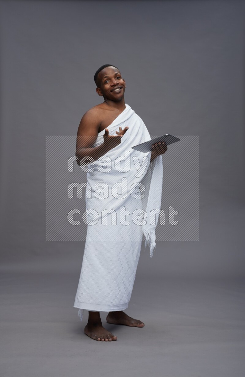 A man wearing Ehram Standing working on tablet on gray background