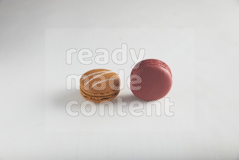 45º Shot of of two assorted Brown Irish Cream, and Red Velvet macarons on white background