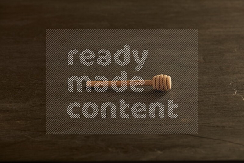 Wooden honey dipper on black slate background