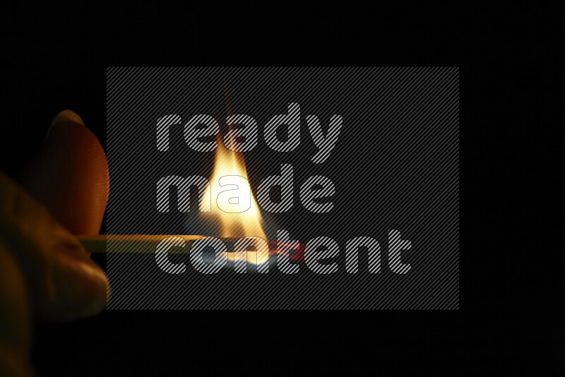 A burning matchstick isolated on dark backdrop