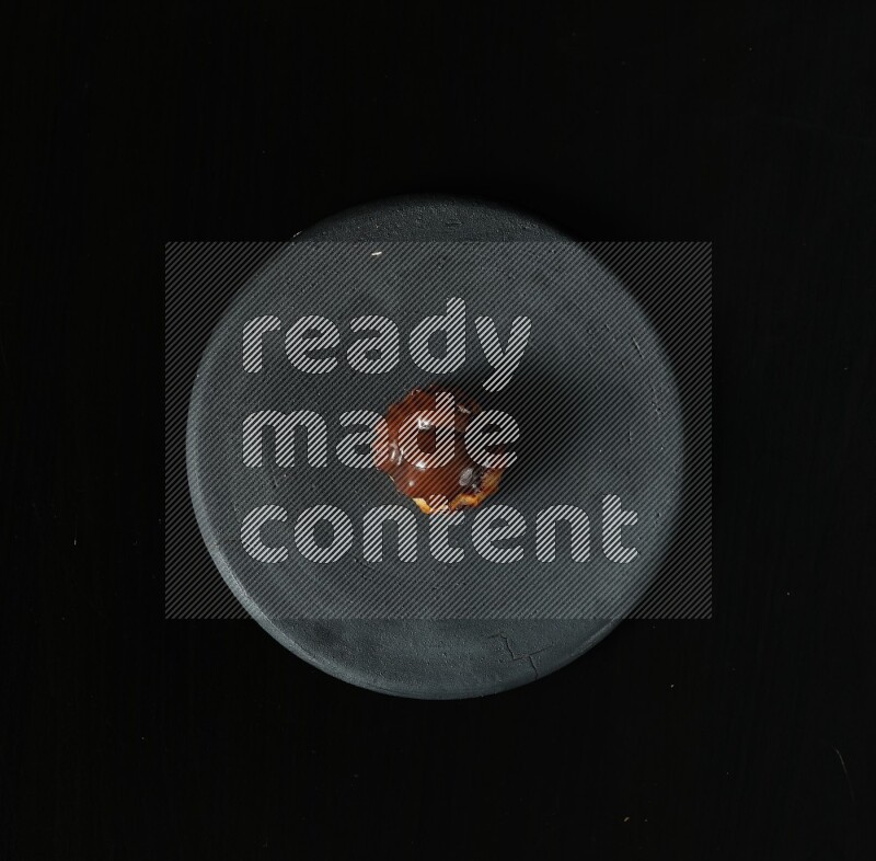 تشكيلة من الحلويات في طبق فخاري أسود على خلفية سوداء