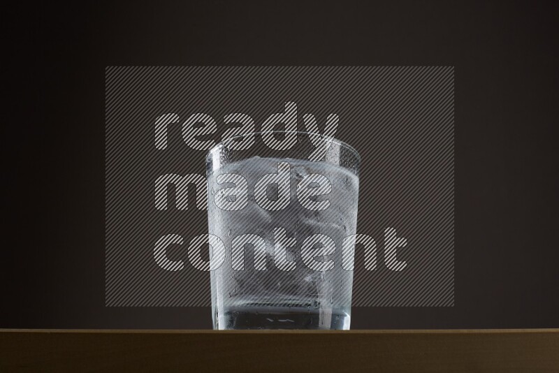 Low angle shot of a glass of water and ice on grey background