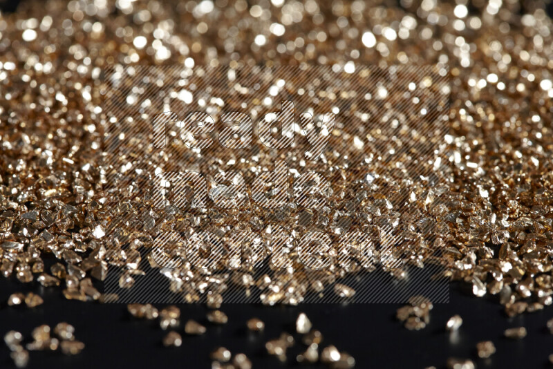 Gold shimmering fragments of glass scattered on a black background