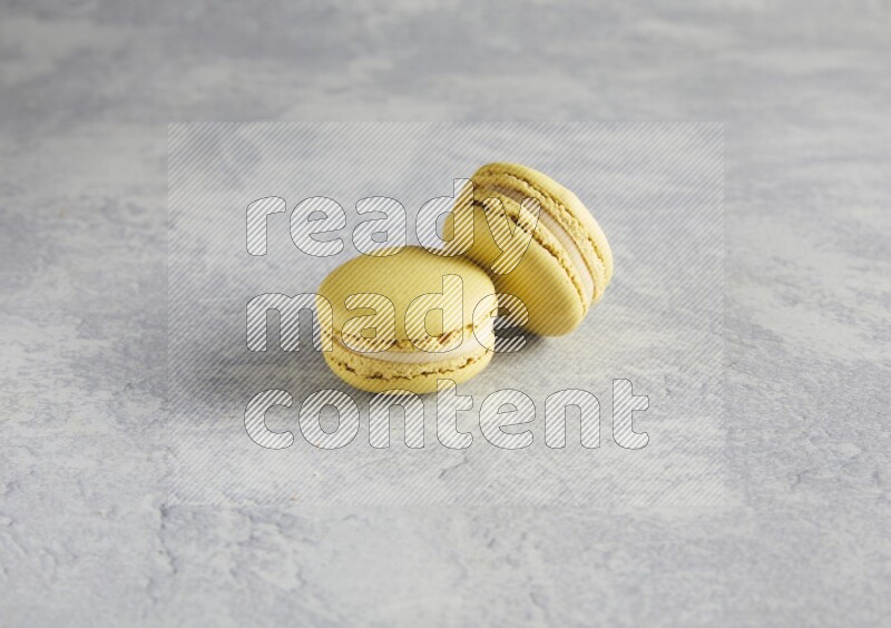45º Shot of two Yellow Lime macarons  on white  marble background
