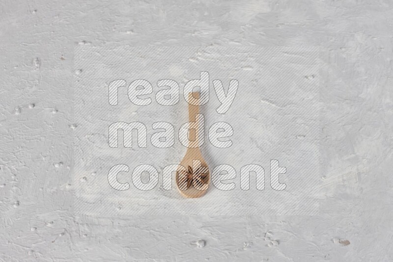 Star Anise in a wooden spoon on white flooring