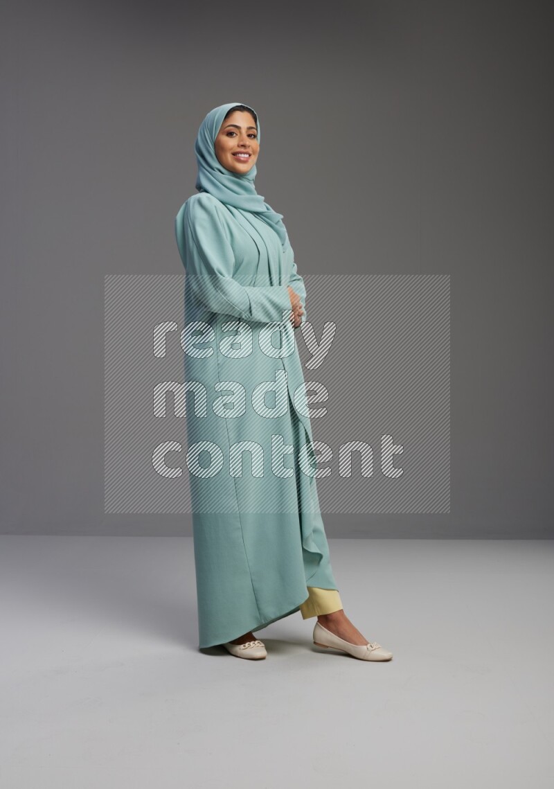 Saudi Woman wearing Abaya standing interacting with the camera on Gray background