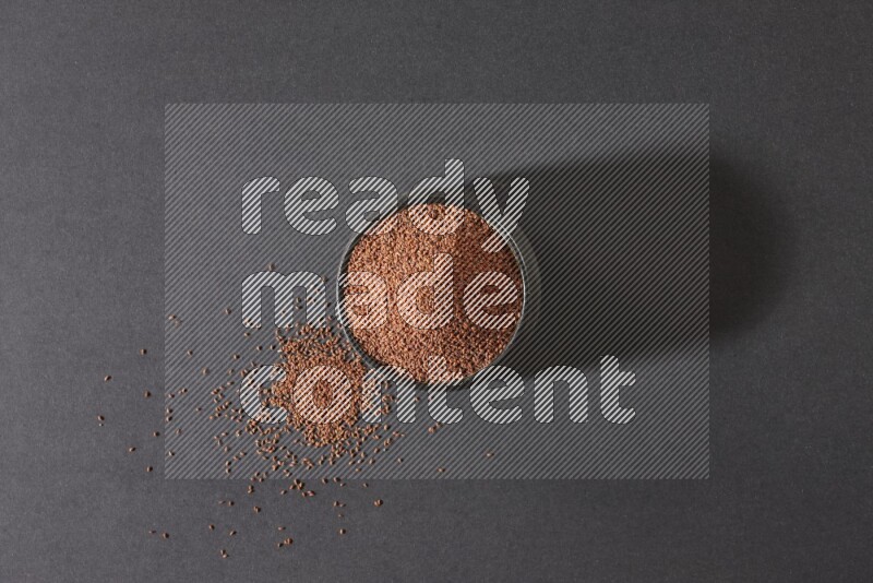 A black pottery bowl full of garden cress seeds on a black flooring