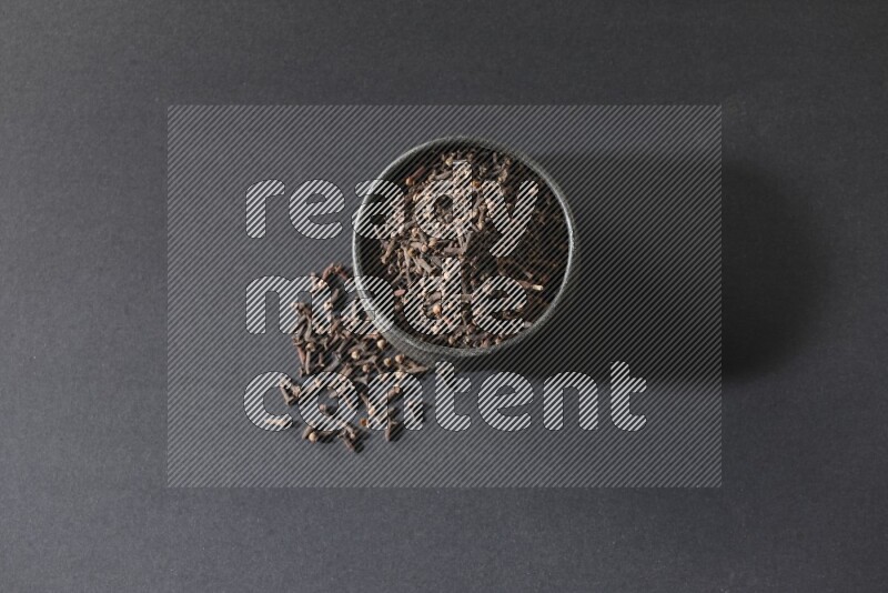 وعاء فخاري أسود ممتلئ بحبوب القرنفل علي خلفية سوداء