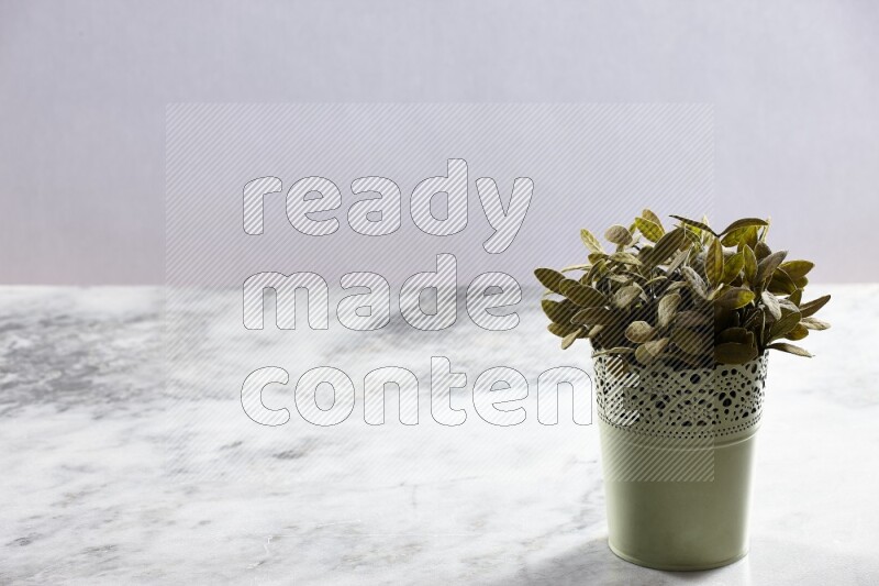 Artificial plant in green decorative pot on grey marble background
