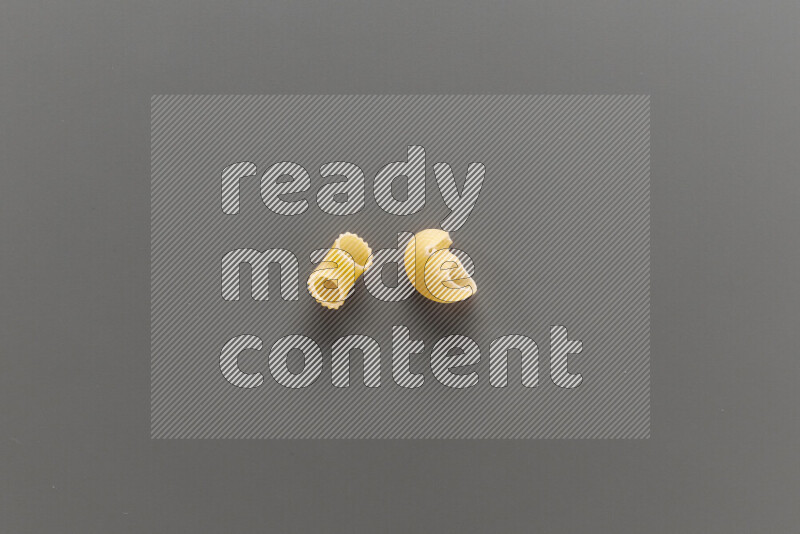 Elbow pasta with other types of pasta on grey background