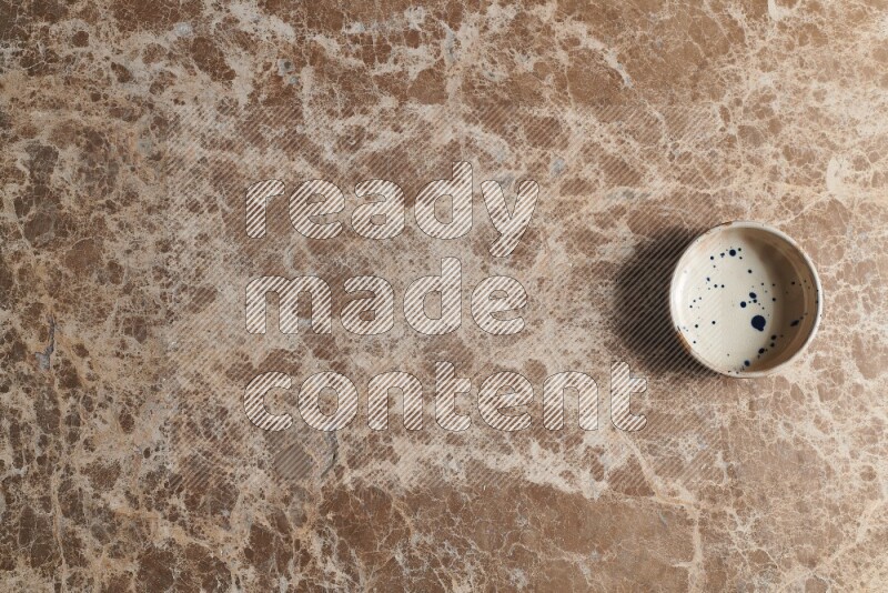 A multicolored pottery bowl on beige marble background