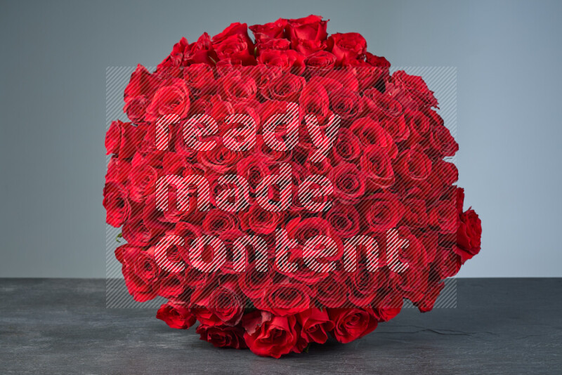 A sphere of vibrant red roses arranged tightly on black marble background