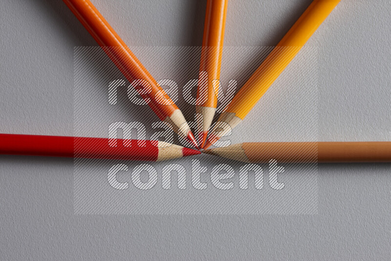 An arrangement of colored pencils in different colors on grey background