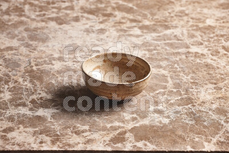 A beige pottery bowl on beige marble background