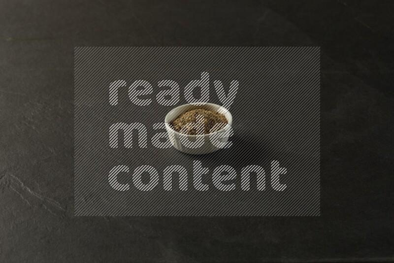 white ceramic round sauce bowl filled with herbs on grey textured countertop