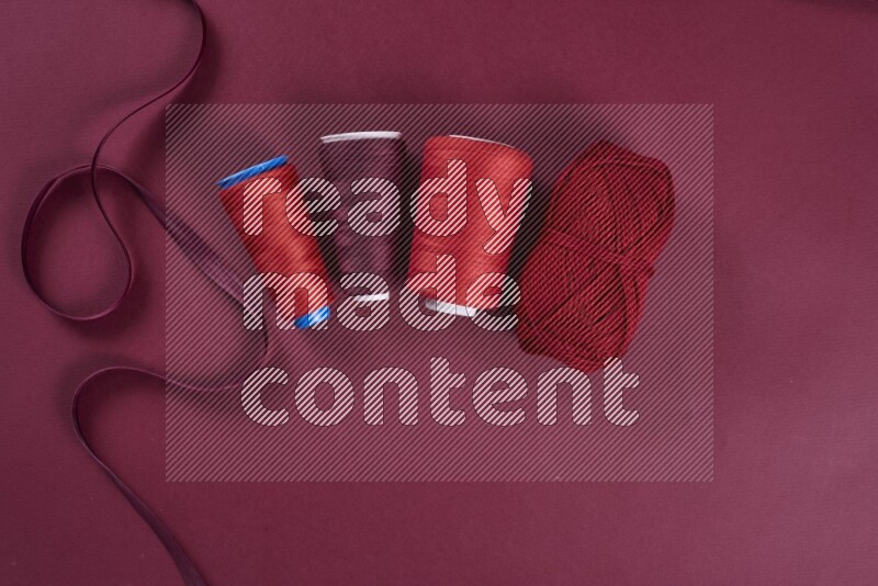 A red collection of sewing and tailoring tools arranged on a red background