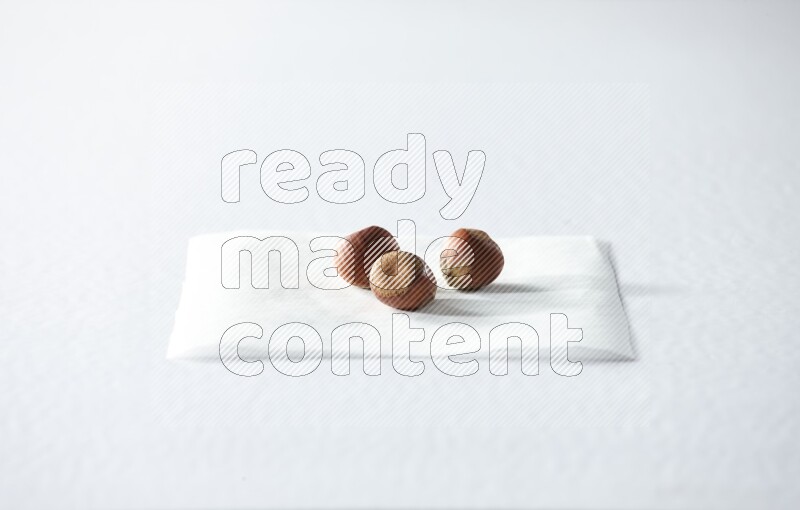 3 hazelnuts on a piece of paper on a white background in different angles