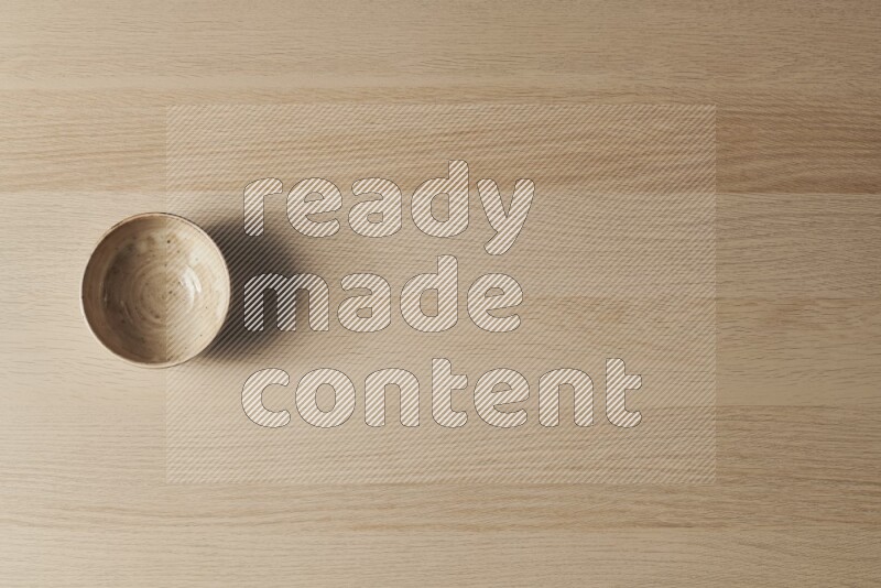 A beige pottery bowl on light wooden background