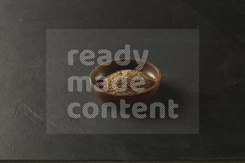 wooden round sauce bowl filled with herbs on grey textured countertop
