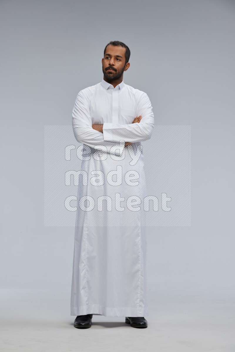 Saudi man wearing Thob standing with crossed arms on Gray background