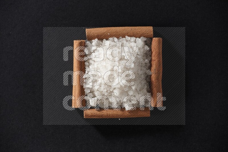A single square of cinnamon sticks full of salt on black flooring