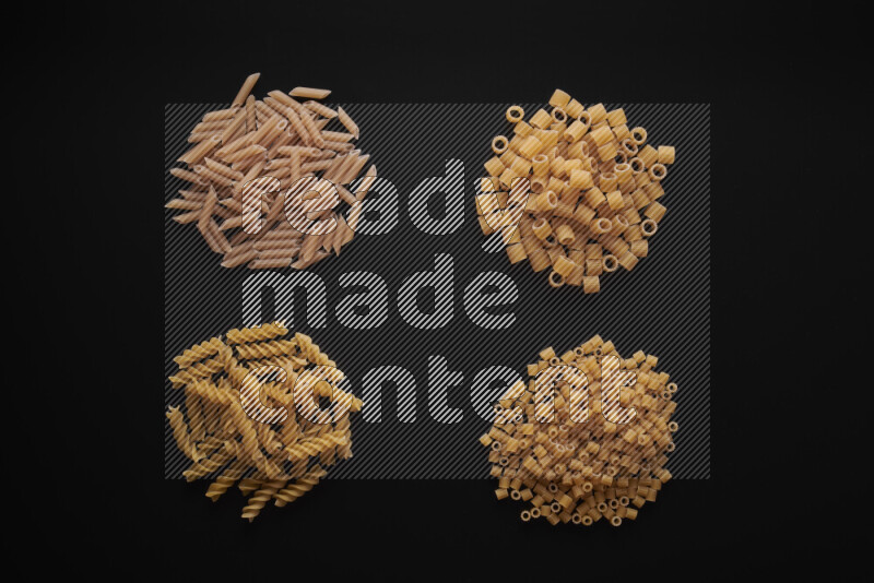 Different pasta types in bunches on black background