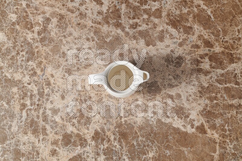 A ceramic milk jug on beige marble background