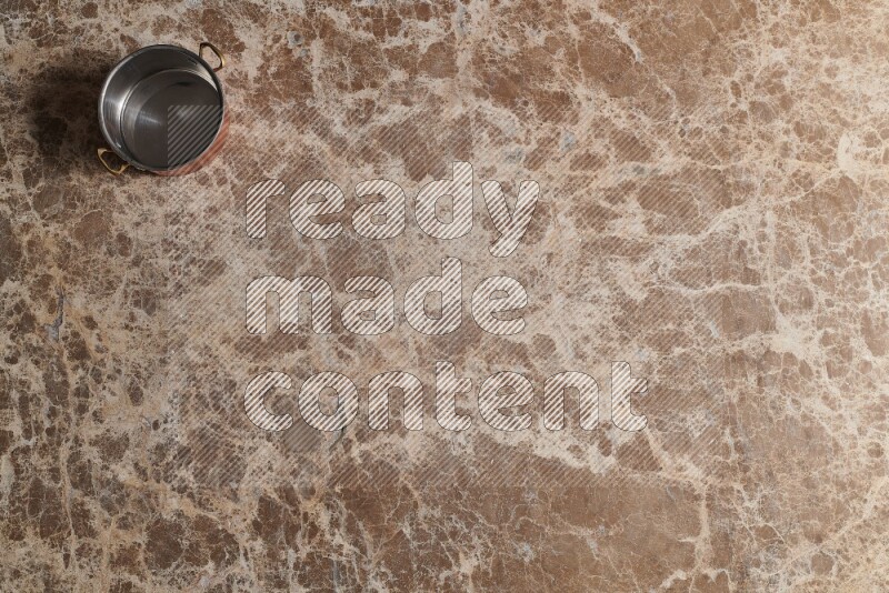 A small copper pot on beige marble background