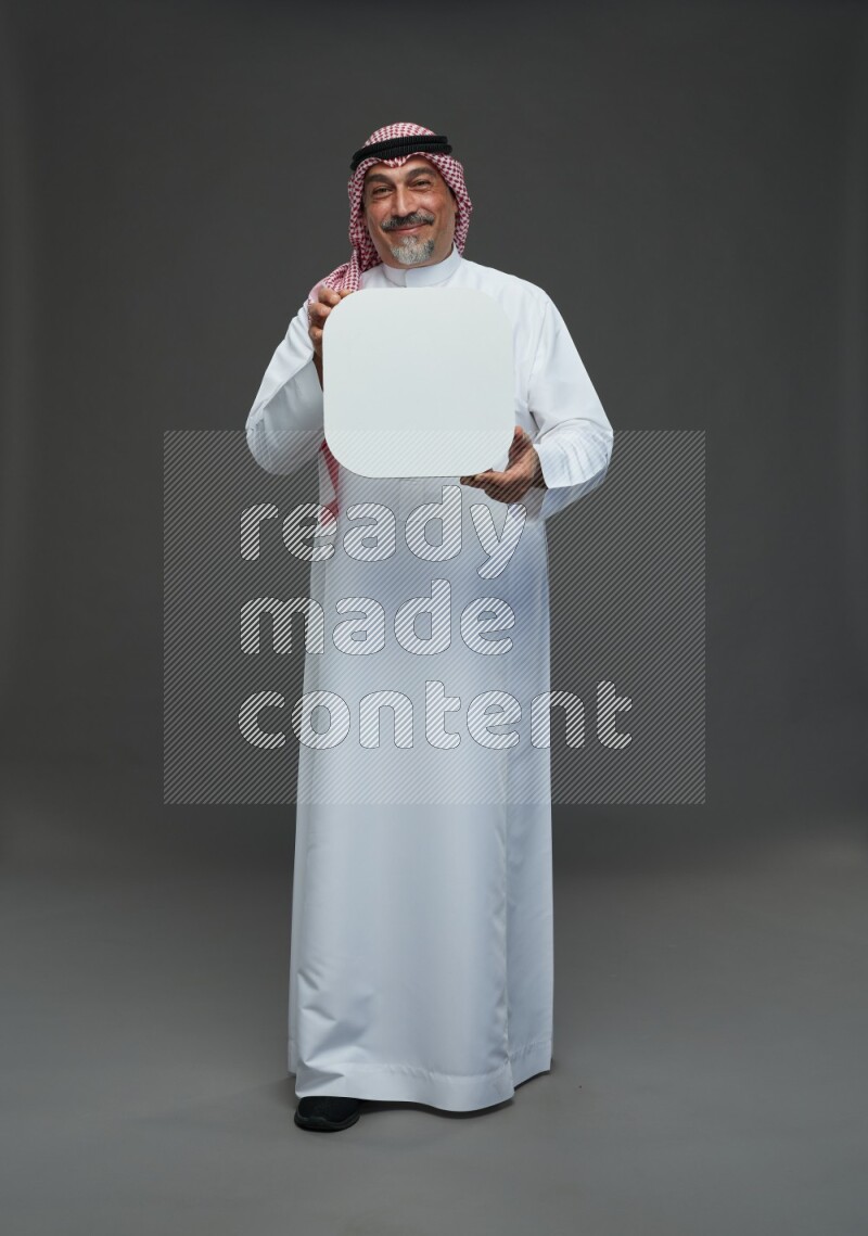 Saudi man with shomag Standing holding social media sing on gray background