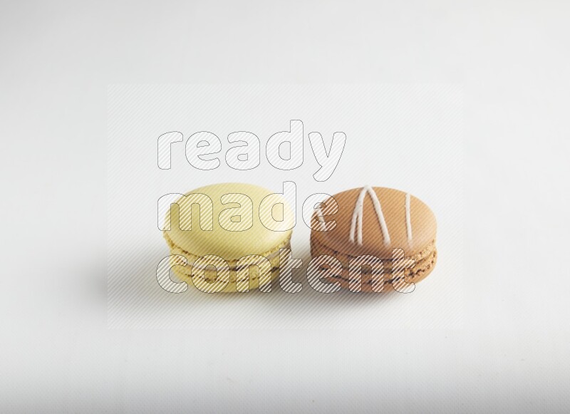 45º Shot of of two assorted Brown Irish Cream, and Yellow Lime macarons on white background