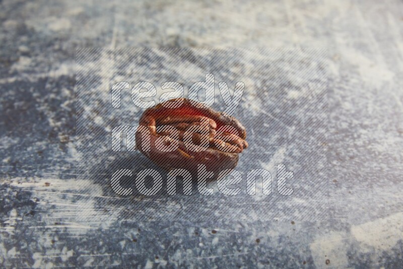 pecan stuffed madjoul date on a rustic blue background