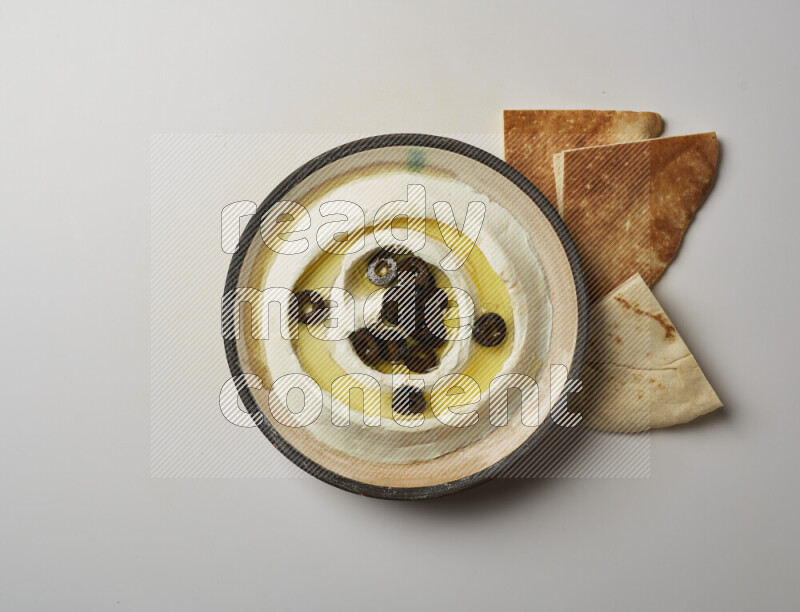 Lebnah garnished with sliced olives in a pottery plate on a white background