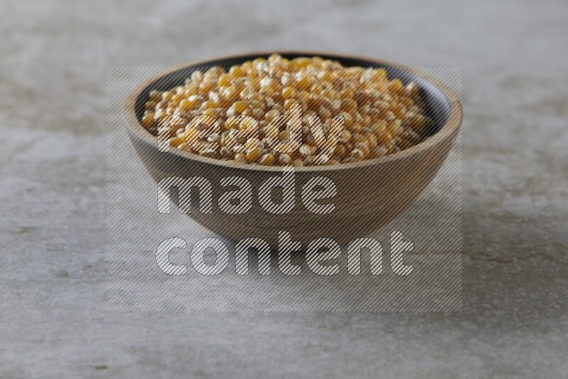 corn kernel in a wooden bowl on a grey textured countertop