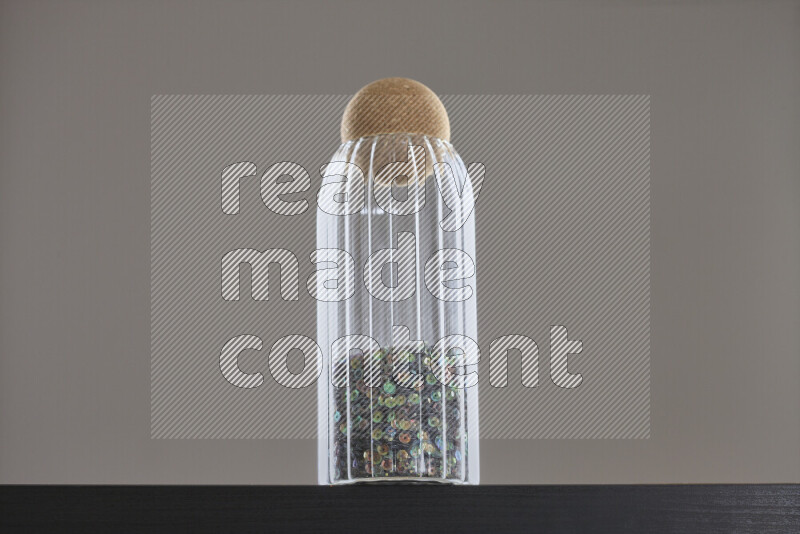 Sequins in a glass jar on black background