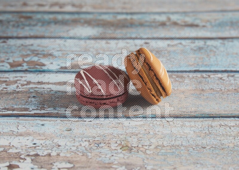 45º Shot of of two assorted Brown Irish Cream, and Red Poppy Flower macarons  on light blue background