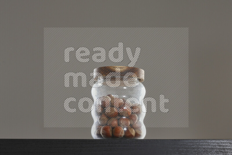 Hazelnuts in a glass jar on black background
